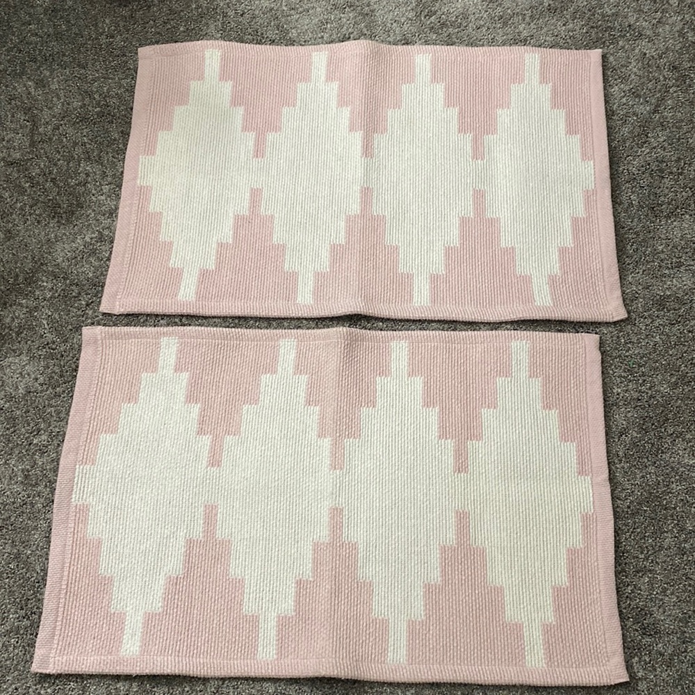 Set of two 20”x34” rugs by Home Essentials. Color is a soft pink and white.